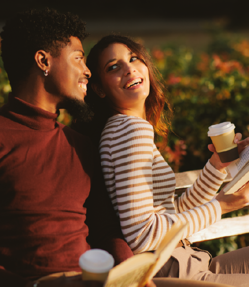 Happy couple reading and drinking coffee together while outside