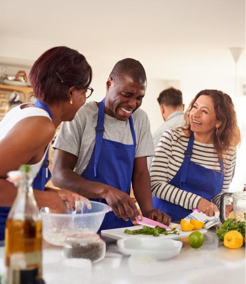 Diverse group of people in blue aprons working together in a kitchen