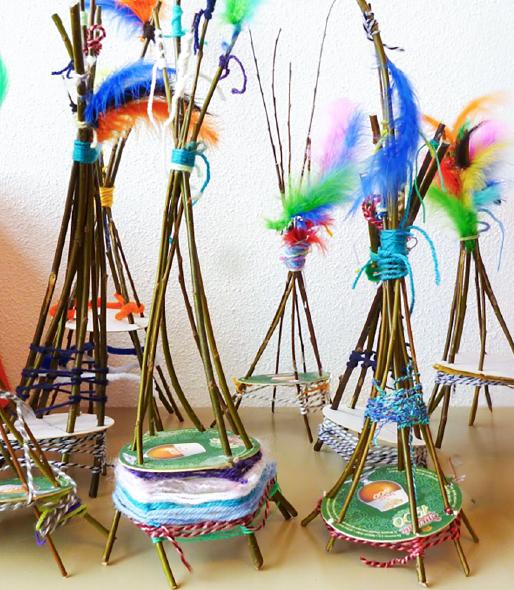 Image: twigs, multicolored yarn, and multicolored feathers put together to create little teepees.