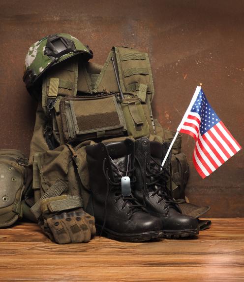 Collection of military boots, gloves, combat helmet, and vest with a US flag