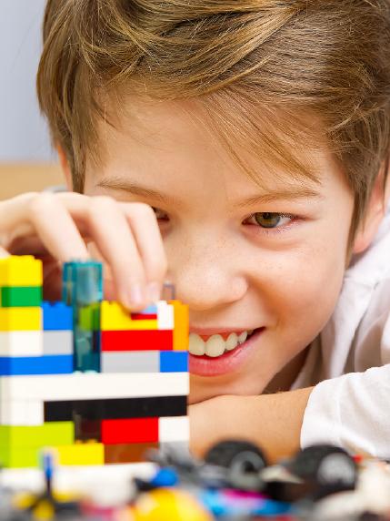 Close up of smiling young boy building with Lego plastic bricks