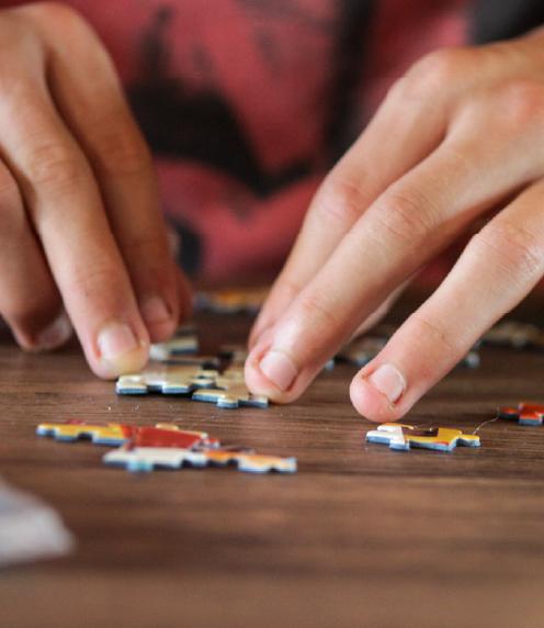 Close up of person's fingers fitting puzzle pieces together